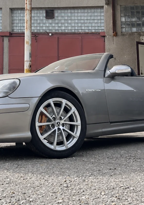 Kolo a pneumatika stříbrného Mercedesu před dílnou Aloha Auto